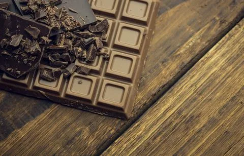 Flat vector milk chocolate bar is resting on weathered plank, revealing dark Foto stock