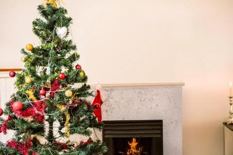 Flat vector is showing Christmas tree with baubles and lights beside lit Stock Photos