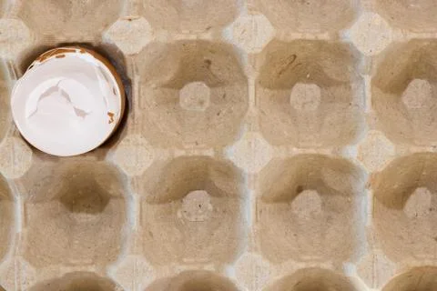 Flat view of a box with broken eggshell brown chicken eggs, background texture Stock Photos