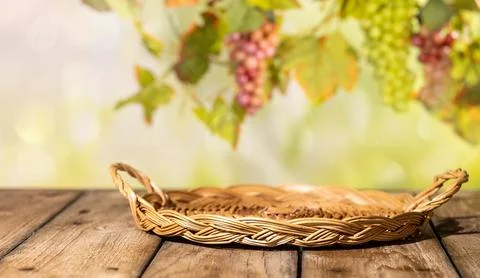 Flat wicker tray on wooden table with blurred grapes and vine leaves for ru.. Foto stock
