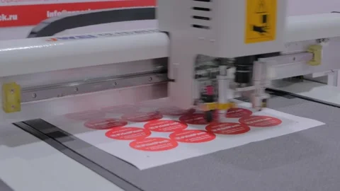 Flatbed cutter, plotter cutting red label stickers at exhibition - close up Stock Footage 142960041