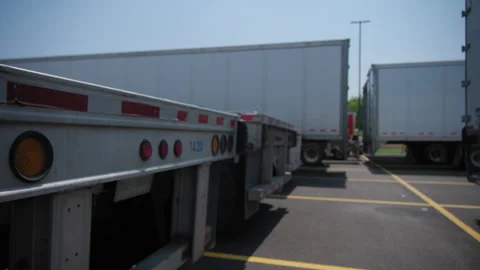 Flatbed trailer and other trailers for semi-trucks in the parking lot Stock Footage 284200346