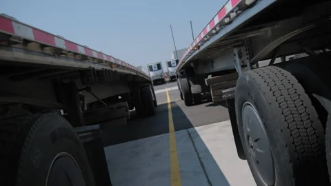 Flatbed trailer and other trailers for semi-trucks in the parking lot. Move Stock Footage 284200610