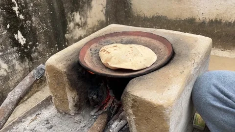 Flatbread being cooked on a clay stove or chulha using firewood Video stock 327858393