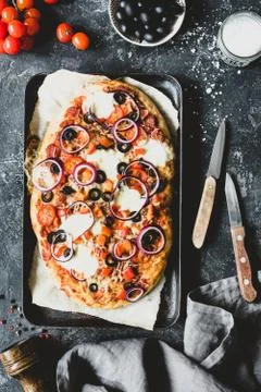 Flatbread pizza with mozzarella and black olives on wooden pizza board, top view Foto stock