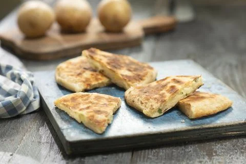 Flatbread with potatoes and cheese, served on the table. Stock Photos