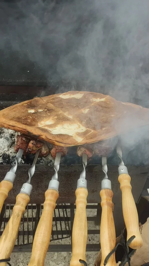 Flatbread warming on skewers over hot coals in a grill. Stock Footage 332582304