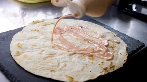 Flatbread wrap drizzled with sauce in slow motion 스톡 동영상 274808635
