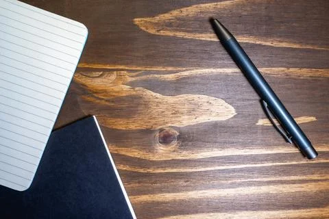 Flatlay background of a pen and a notebook, on a wooden background Stock Photos