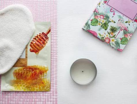 Flatlay bath accessories on white background. Top view candle, notebook, mask. Stock Photos