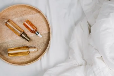 Flatlay of bed with white sheets, blankets and wooden tray with body, face or Stock Photos