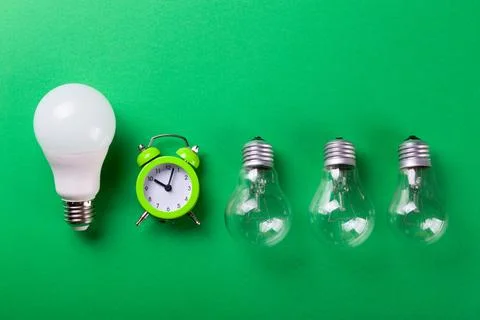 Flatlay Clock with light bulb, calculator on a green background. Minimalism.. Stock Photos