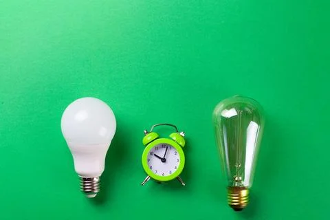 Flatlay Clock with light bulb, calculator on a green background. Minimalism.. Stock Photos