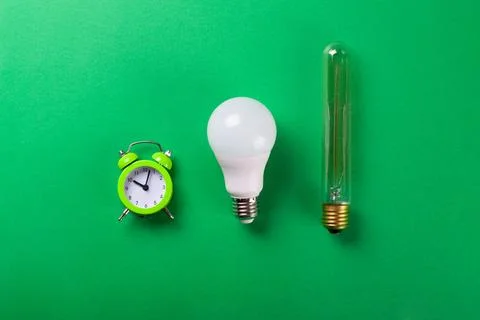 Flatlay Clock with light bulb, calculator on a green background. Minimalism.. Stock Photos