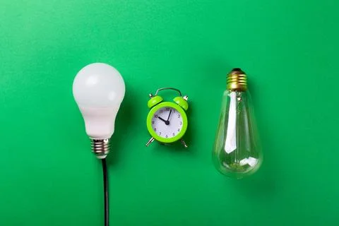 Flatlay Clock with light bulb, calculator on a green background. Minimalism.. Stock Photos