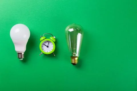 Flatlay Clock with light bulb, calculator on a green background. Minimalism.. Stock Photos