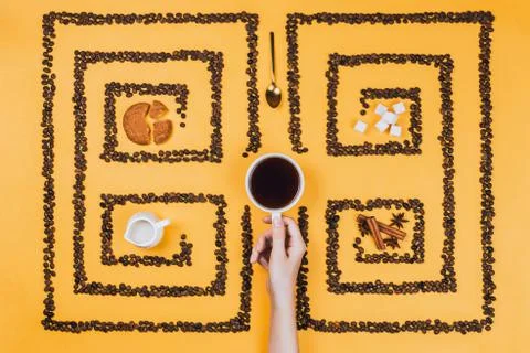 Flatlay of coffee cup in the middle of pattern or labyrinth made of coffee be Stock Photos