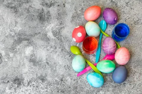 Flatlay, colorful dyed easter eggs, spoons and egg dyes on grey background, c Stock Photos