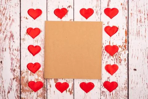 Flatlay composition with hearts and a sheet of paper on a wooden background Stock Photos