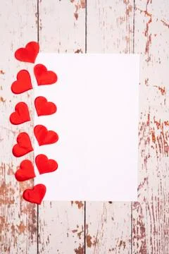 Flatlay composition with hearts and a sheet of paper on a wooden background Stock Photos