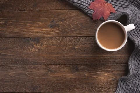 Flatlay composition with knitted scarf, cup of coffe on wooden desk table. Hy Stock Photos