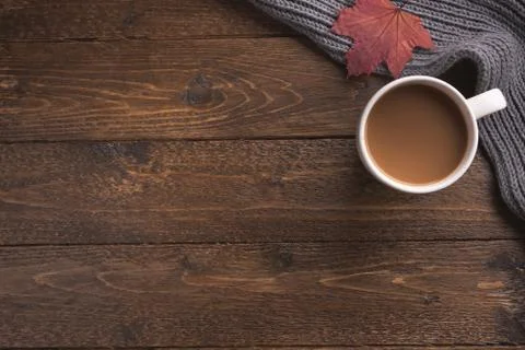 Flatlay composition with knitted scarf, cup of coffe on wooden desk table. Hy Stock Photos