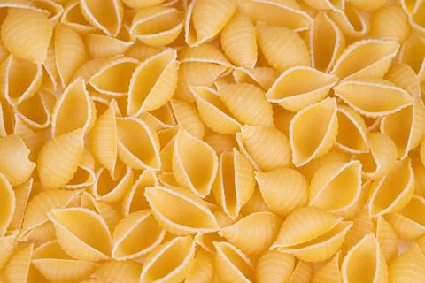 Flatlay composition of yellow pasta shells with crisp edges and even colors.. 스톡 사진