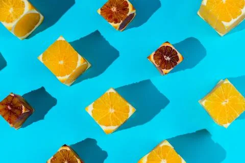 Flatlay of cubes cut out of various oranges on blue Stock Photos