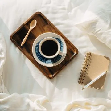 Flatlay with cup of coffee or tea on wooden tray with notebook and pen on sid Stock Photos