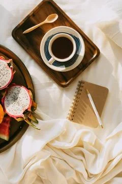 Flatlay with cup of coffee or tea on wooden tray and tropical fruit plate wit Stock Photos
