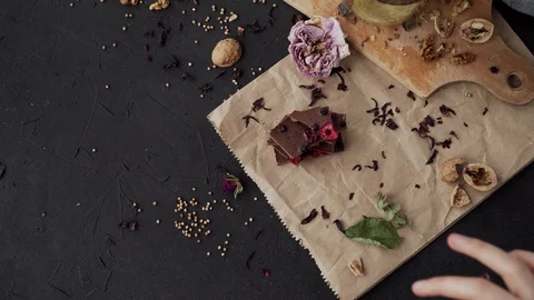 Flatlay on dark background with chocolate, walnut, wood board and paper Video stock 90525110