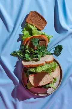 Flatlay of different kind of bread with various greens on a blue drapery, con Stock Photos