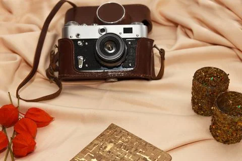 Flatlay. Film camera in case, notebook, fisalis and candlesticks lie on a bei Stock Photos