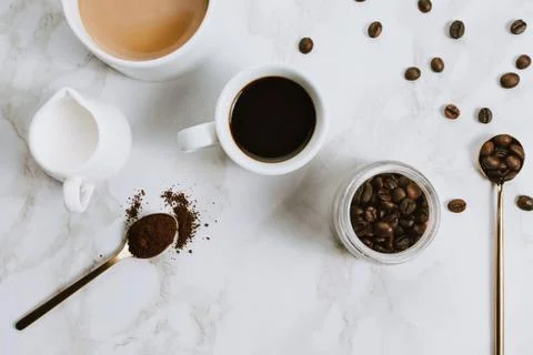Flatlay of fresh cups of espresso and milk coffee, creamer, coffee beans and  Stock Photos