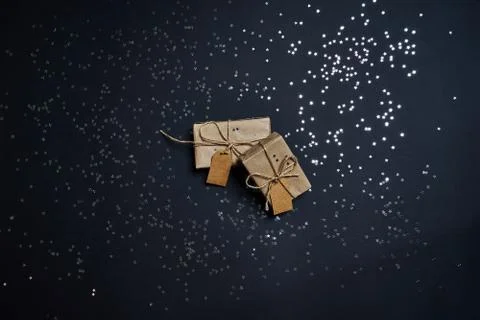 Flatlay of gift boxes and silver glitter sparklings confetti on dark background. Stock Photos