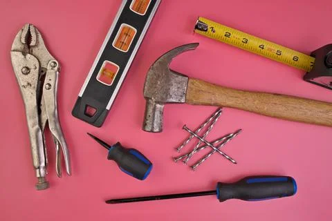 Flatlay of Hand Tools on Pink Background Including Hammer, Nails, Tape Measure Stock Photos