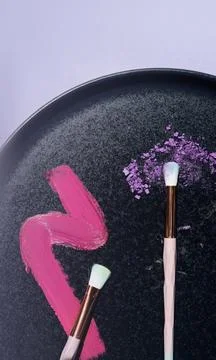 Flatlay of makeup brushes and makeup on a black plate Stock Photos