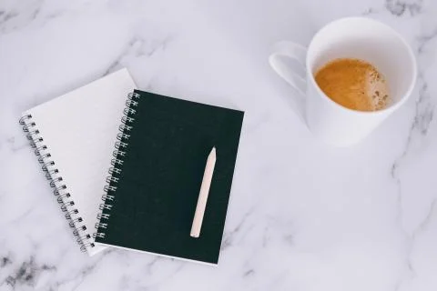 Flatlay of mini spiral notebooks with pencil and cup of coffee on marble desk Stock Photos
