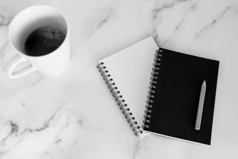 Flatlay of mini spiral notebooks with pencil and cup of coffee on marble desk Stock Photos