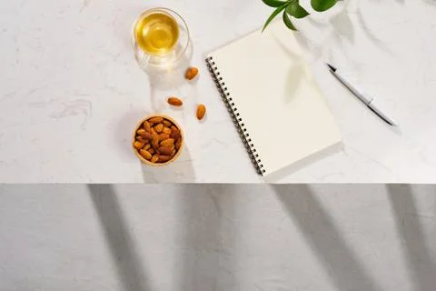 Flatlay of notebook, cake macaron, cup of tea and leaves on white table Fotos Stock