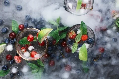 Flatlay of three cups with iced soda water on dark background with mint, herb Stock Photos