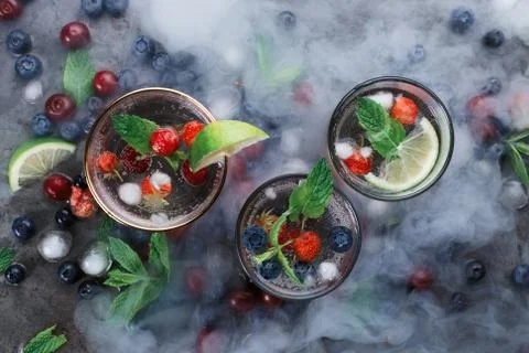 Flatlay of three cups with iced soda water on dark background with mint, herb Stock Photos