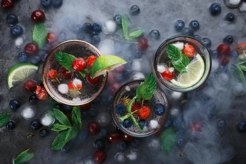 Flatlay of three cups with iced soda water on dark background with mint, herb Stock Photos