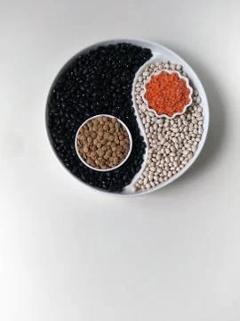 Flatlay, top view, four colors of beans on a Yin Yang plate, white haricot, l Stock Photos