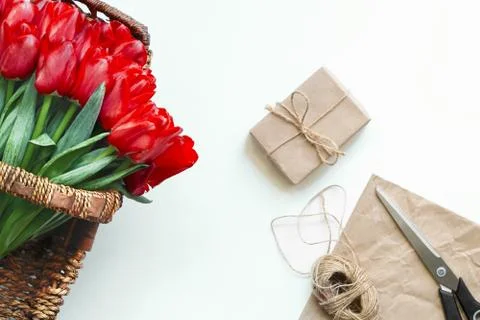 Flatlay of tullips and craft wrapping paper, ribbon, scissors and present. Stock-Fotos