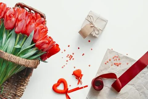 Flatlay of tullips and craft wrapping paper, red ribbon and present. Stock Photos