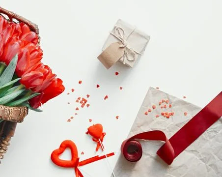 Flatlay of tullips and craft wrapping paper, red ribbon and present. Stock Photos