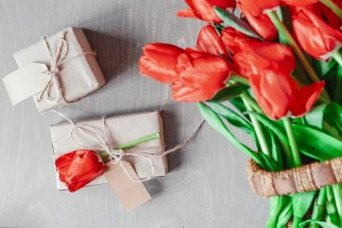 Flatlay of tullips and present wrapped in craft paper. Summer or spring time. Stock Photos