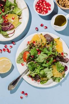 Flatlay of two citrus salad plates  with pomegranate seeds, nut and olive oil Stock Photos