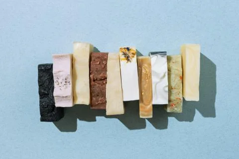 Flatlay of various natural hand-made soaps on blue, selective focus Stock Photos
